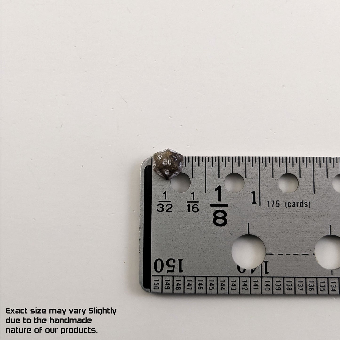 A size graphic of the d20 stud. The stud is brown with white numbers and centers the 20 face next to a ruler on a white background. The ruler shows the width of the stud as 7 mm or 0.27 in. The lower lefthand corner has a disclaimer that reads, "Exact size may vary slightly due to the handmade nature of our products."
