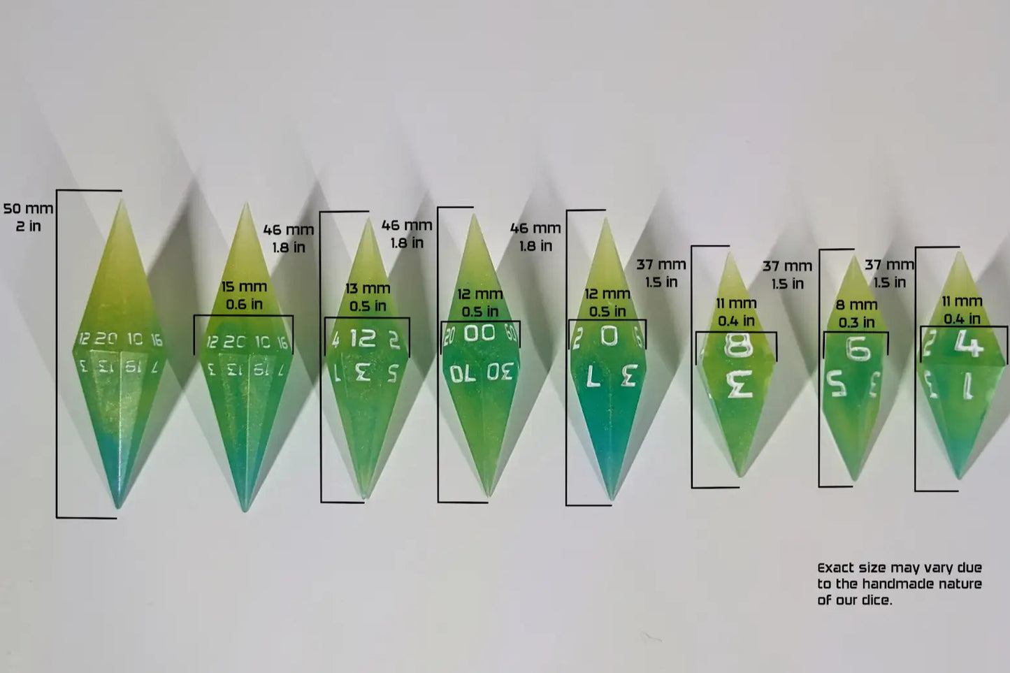 Top-down view of a yellow and green diamond handmade dice set arranged in a line with size labels added digitally. The graphic overlays show the d20 at 50mm (2in) in height and 15mm (.6in) in width, the d12 and d10 resin dice at 46mm (1.8in) in height and 12mm (.5in) in width, the d8 and d4 at 37mm (1.5in) in height and 11mm (.4in) in width, and the d6 at 37mm (1.5in) in height and 8mm (.3in) in width, illustrating the scale of these artisan dice.