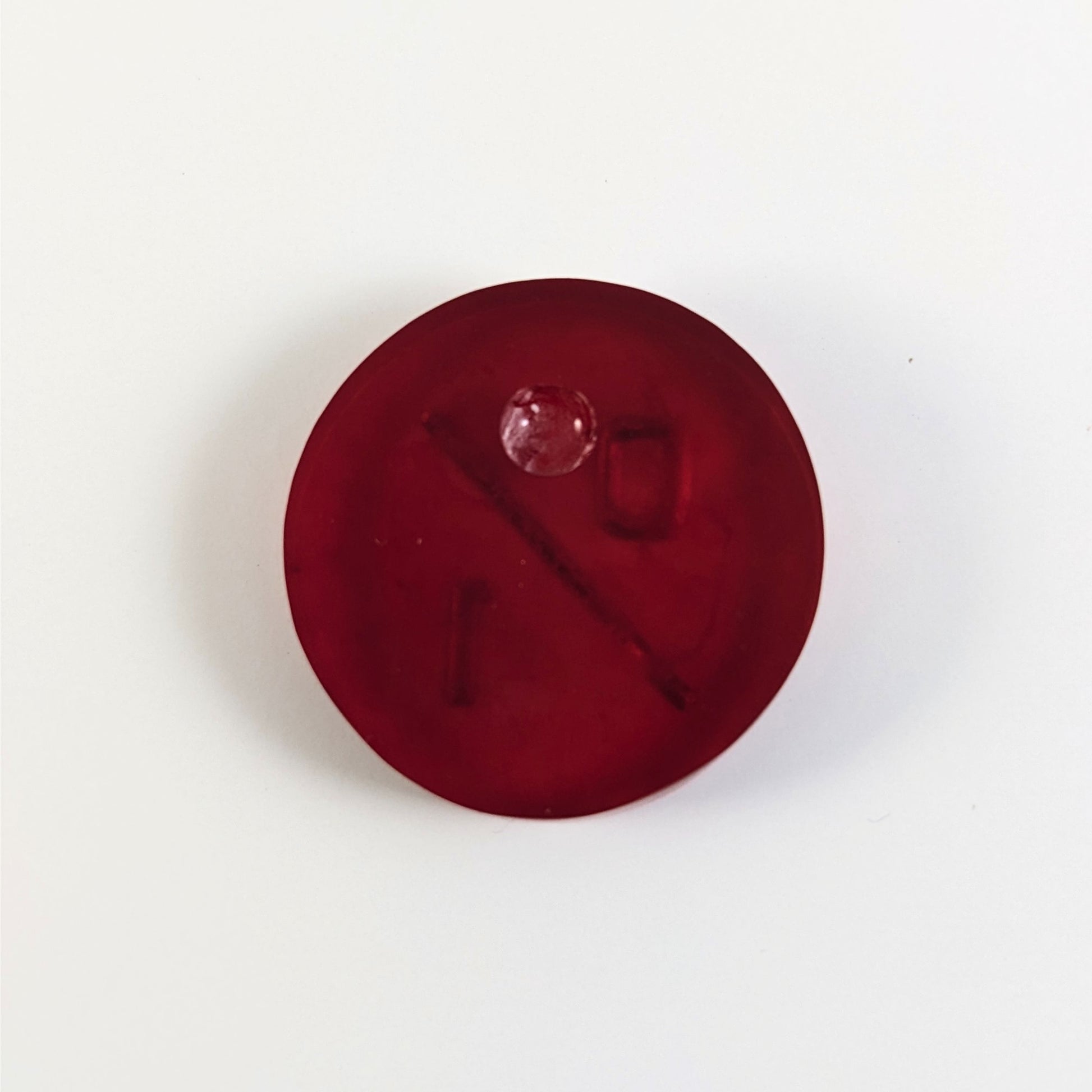 A top down photo of the back of a red 0/1 token with silver numbers sitting on a white background. A bubble is visible.