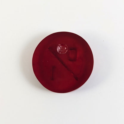 A top down photo of the back of a red 0/1 token with silver numbers sitting on a white background. A bubble is visible.