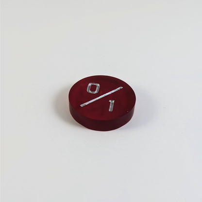 A low angle photo of a red 0/1 token with silver numbers sits on a white background. The cosmetic flaw is not apparently visible at this angle.