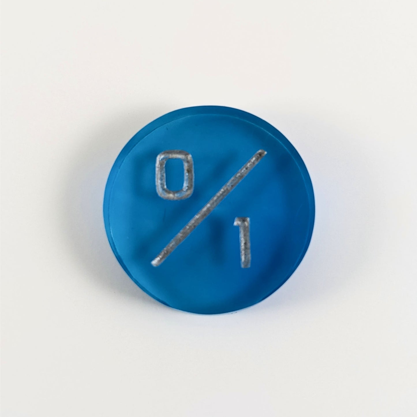 A top down photo of a blue 0/1 token with silver numbers sits on a white background.