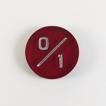 A top down photo of a red 0/1 token with silver numbers sits on a white background.