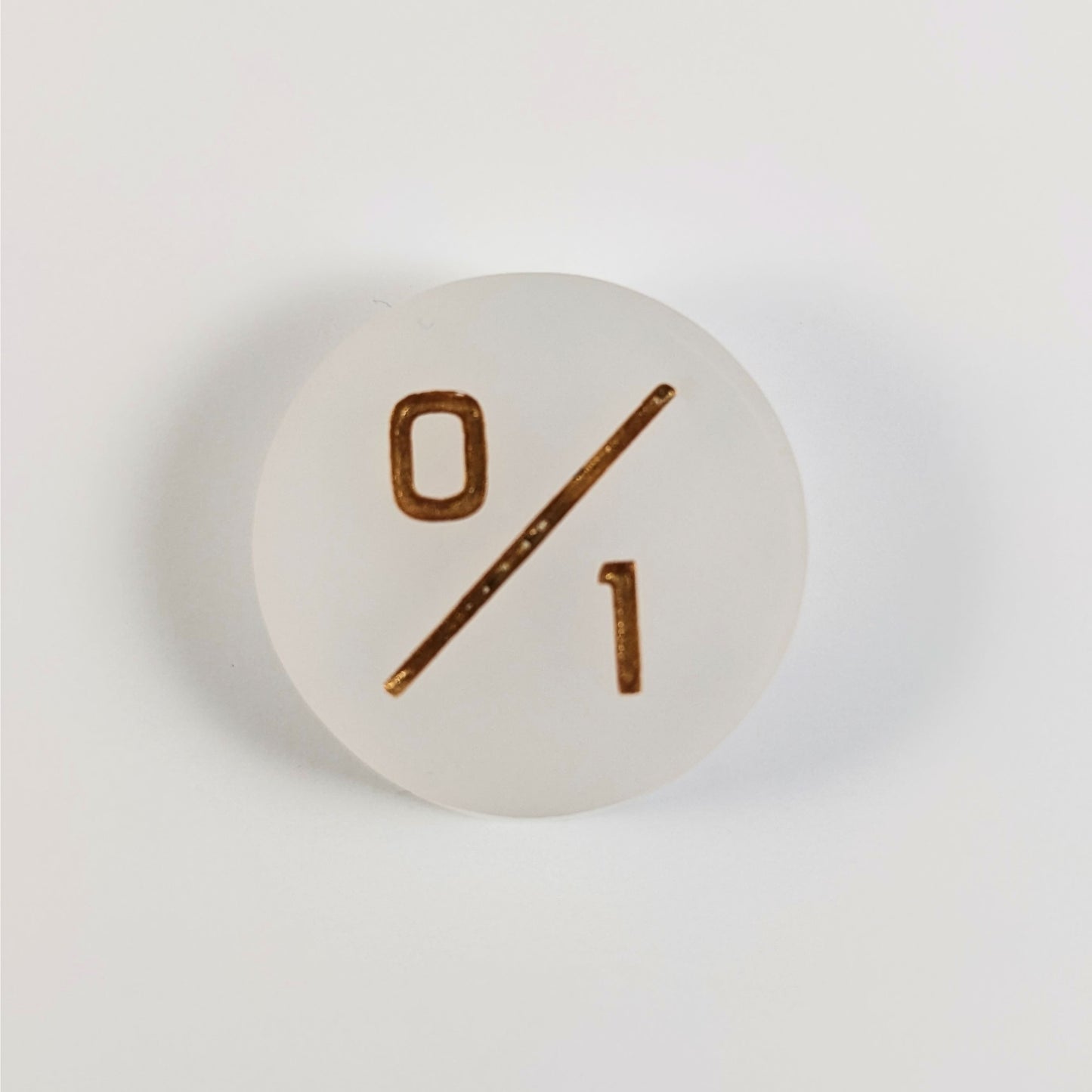 A top down photo of a white 0/1 token with gold numbers sits on a white background.