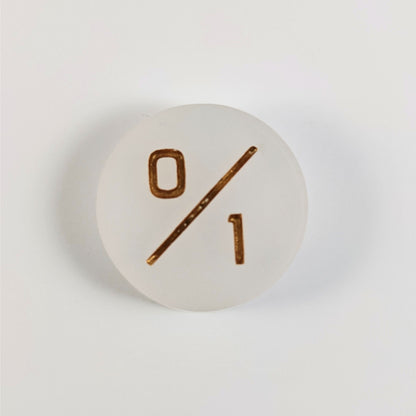 A top down photo of a white 0/1 token with gold numbers sits on a white background.