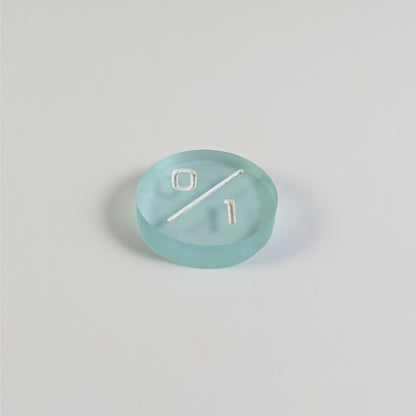 A low angle photo of a frosty white and blue 0/1 token with white numbers sits on a white background.