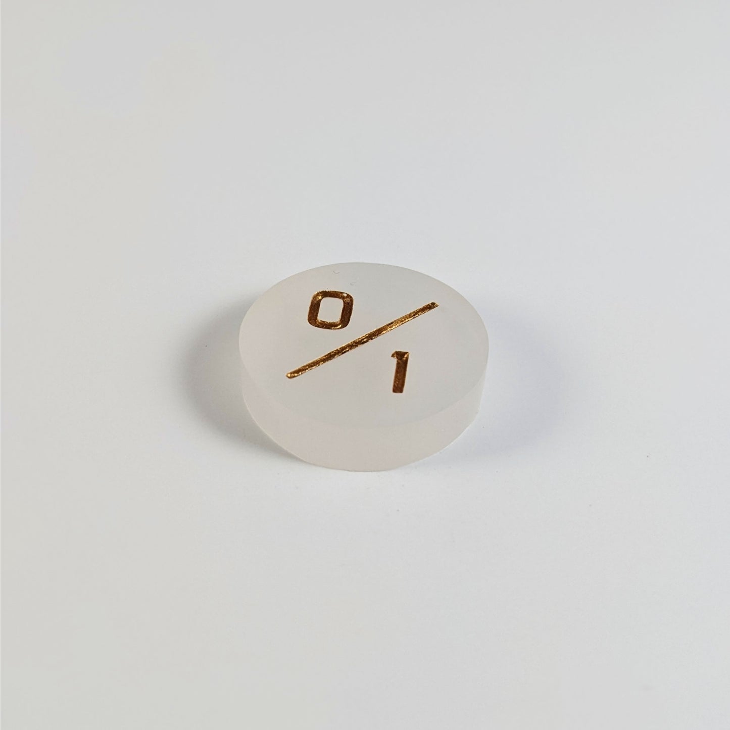 A low angle photo of a white 0/1 token with gold numbers sits on a white background.