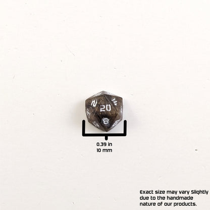 A size graphic of the d20 stud. The stud is brown with white numbers and centers the 20 face on a white background. The graphic overlay shows the width of the stud as 10 mm or 0.39 in. The lower righthand corner has a disclaimer that reads, "Exact size may vary slightly due to the handmade nature of our products."