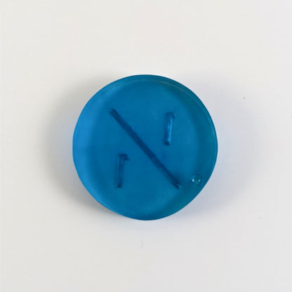 A top down photo of the back of a blue 1/1 token with silver numbers sitting on a white background. A bubble is visible.