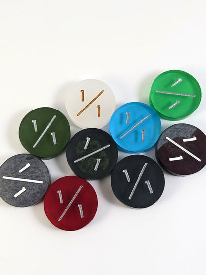 A collection of 1/1 tokens in a variety of colors on a white background. Each token is face up.