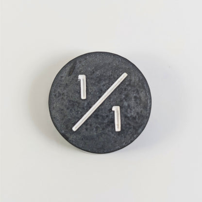 A top down photo of a silver 1/1 token with white numbers sits on a white background.