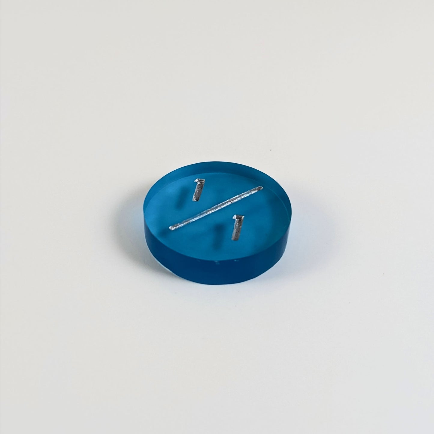 A low angle photo of a blue 1/1 token with silver numbers sits on a white background.