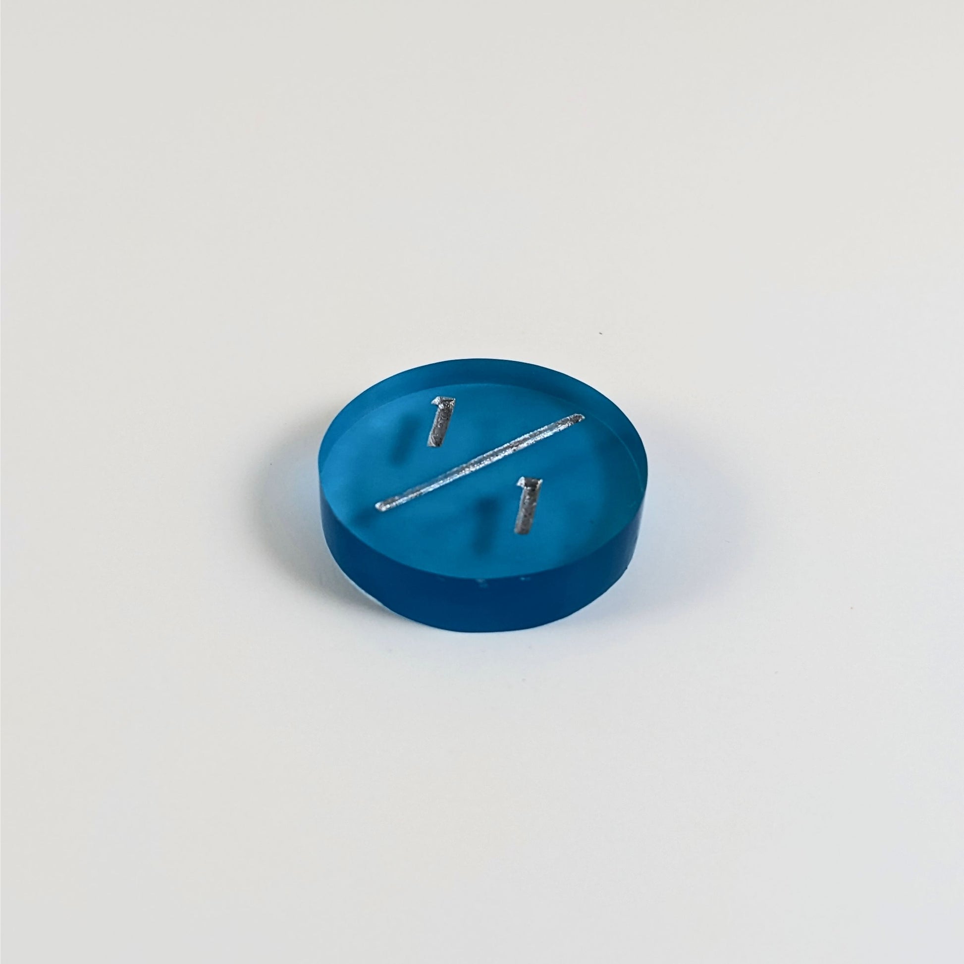 A low angle photo of a blue 1/1 token with silver numbers sits on a white background.