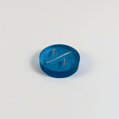 A low angle photo of a blue 1/1 token with silver numbers sits on a white background.
