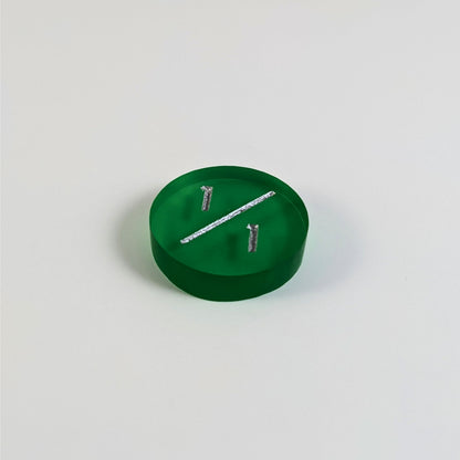 A low angle photo of a green 1/1 token with silver numbers sits on a white background.