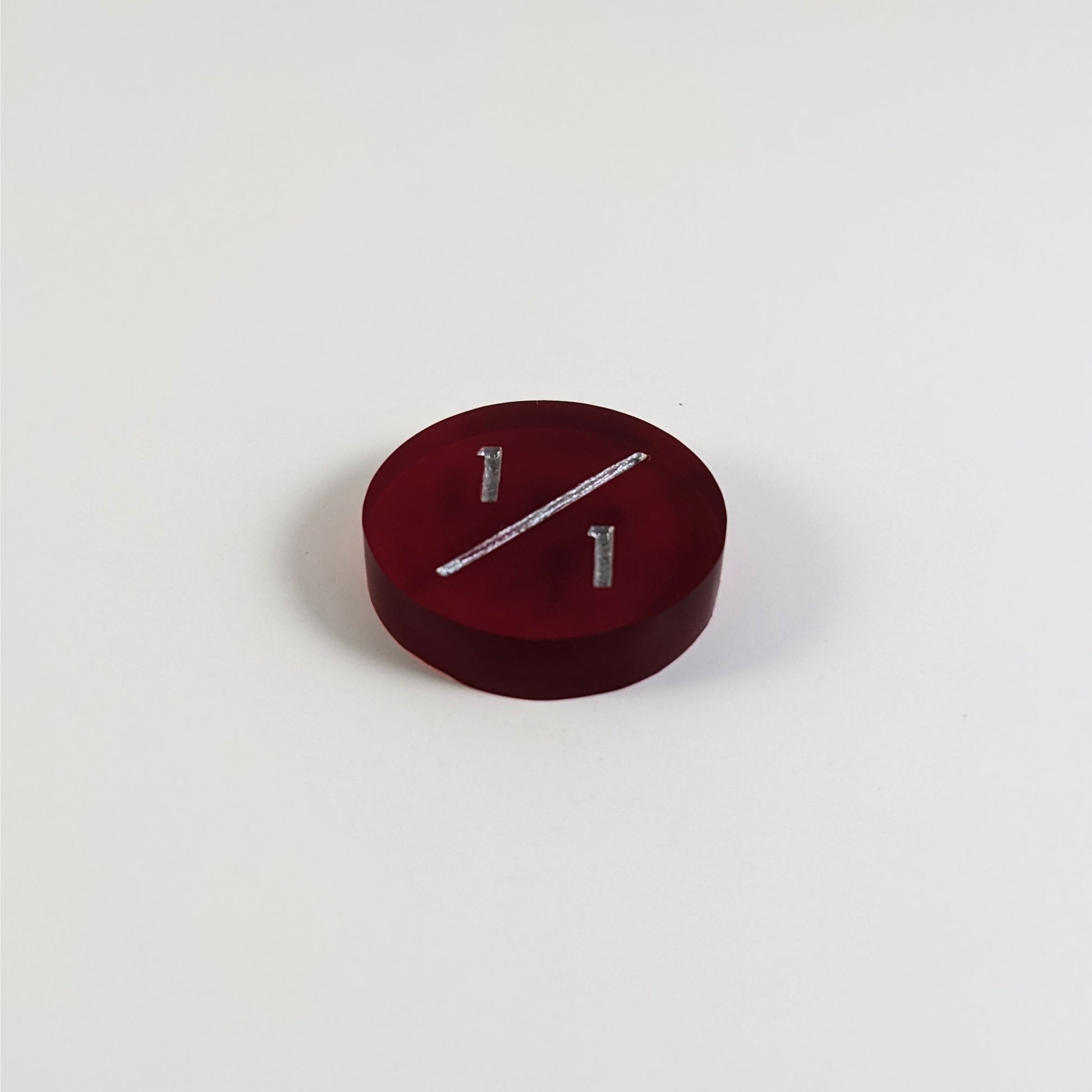 A low angle photo of a red 1/1 token with silver numbers sits on a white background.