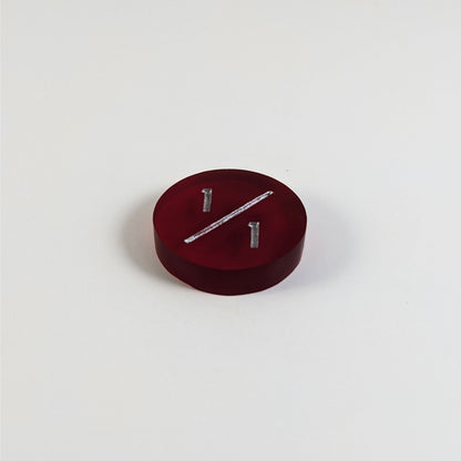 A low angle photo of a red 1/1 token with silver numbers sits on a white background.