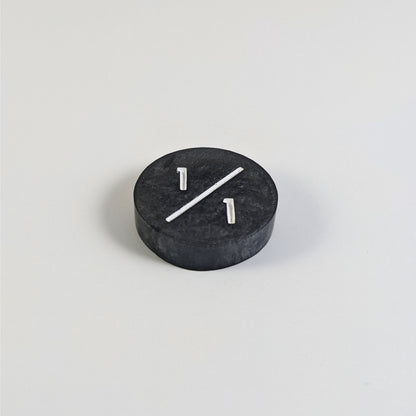 A low angle photo of a silver 1/1 token with white numbers sits on a white background.