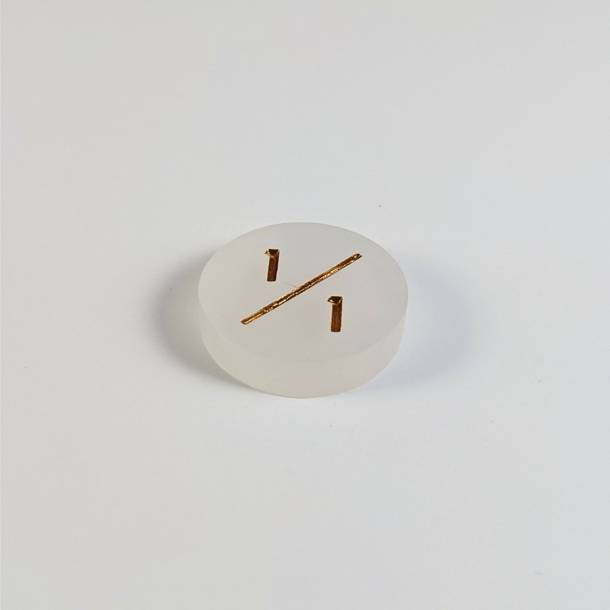 A low angle photo of a white 1/1 token with gold numbers sits on a white background.
