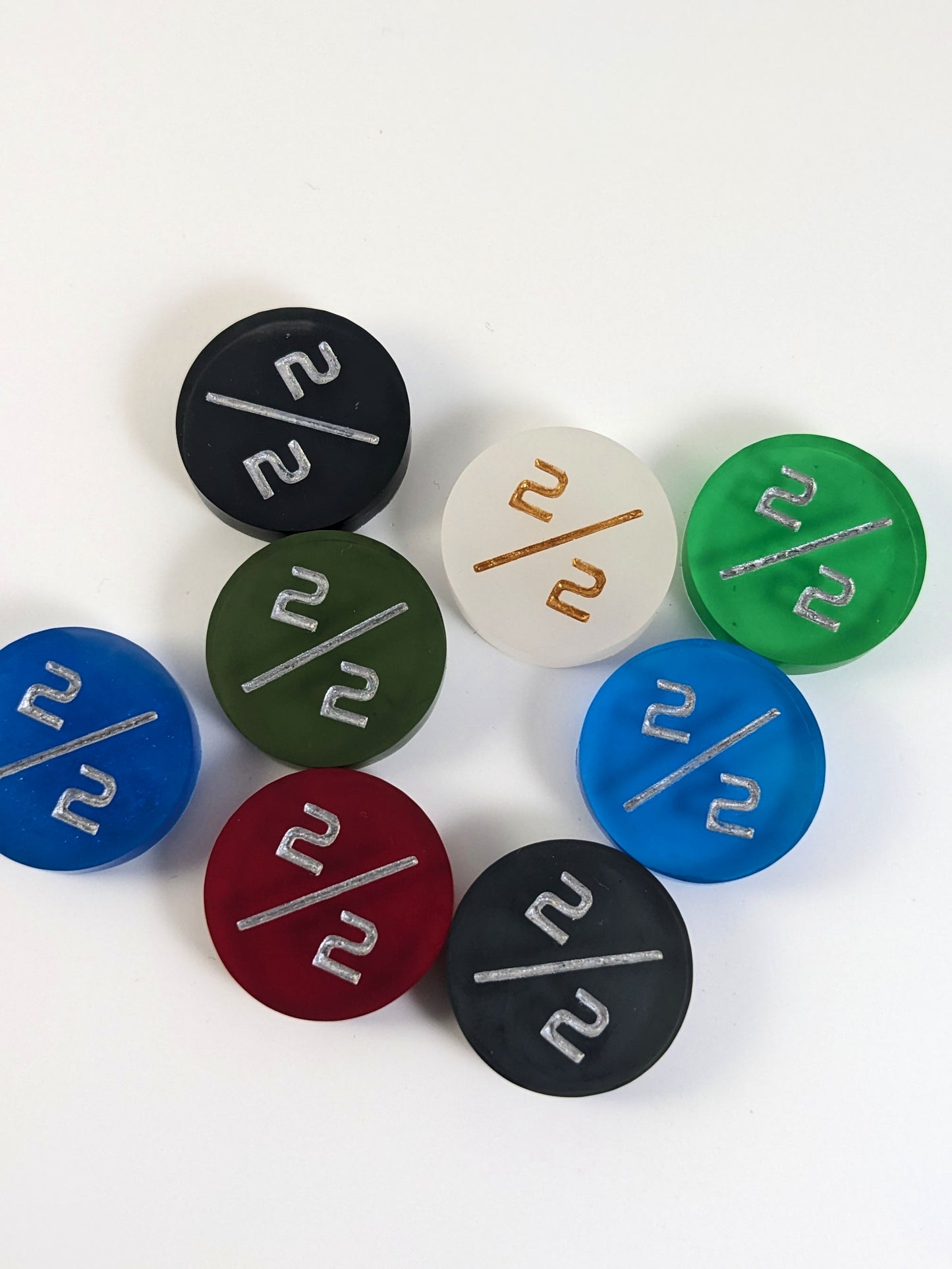 A collection of 2/2 tokens in a variety of colors on a white background. Each token is face up.