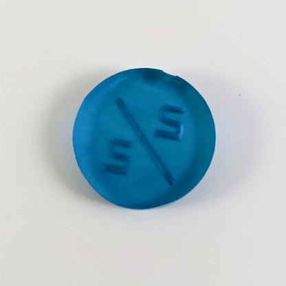 A top down photo of the back of a blue 2/2 token with silver numbers sitting on a white background. A bubble is visible on the tope edge.