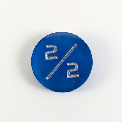 A top down photo of a sapphire blue 2/2 token with silver numbers sits on a white background.