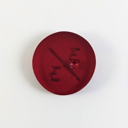 A top down photo of the back of a red 3/3 token with silver numbers sitting on a white background. A bubble is visible.