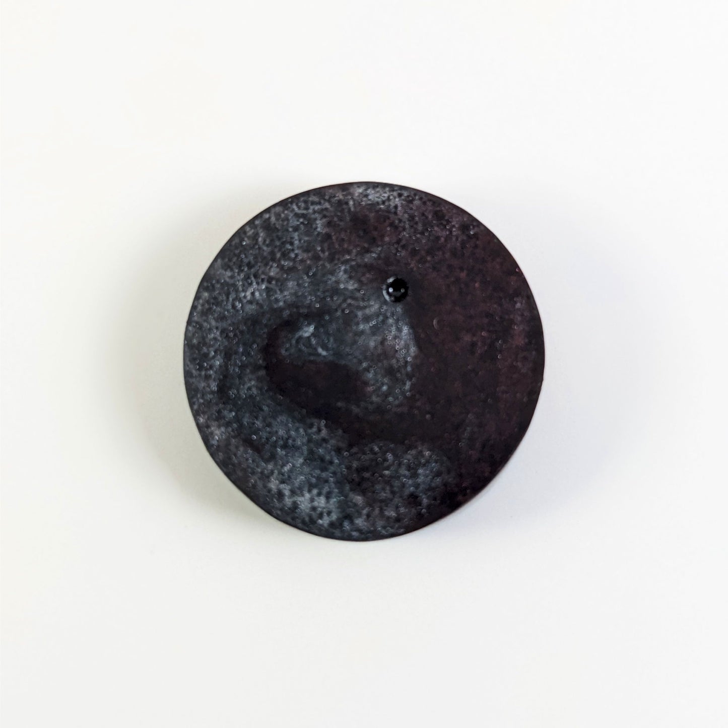 A top down photo of the back of a silver and maroon 4/4 token with white numbers sitting on a white background. A bubble is visible.