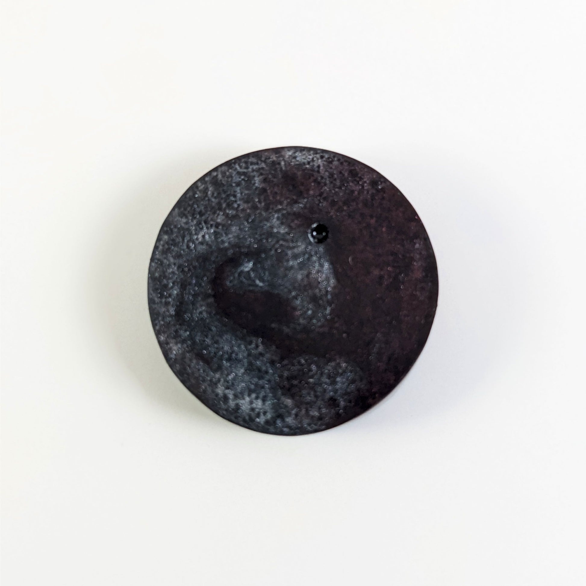 A top down photo of the back of a silver and maroon 4/4 token with white numbers sitting on a white background. A bubble is visible.