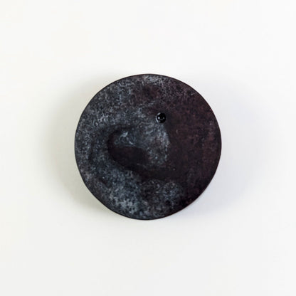 A top down photo of the back of a silver and maroon 4/4 token with white numbers sitting on a white background. A bubble is visible.