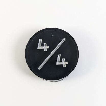 A top down photo of a black 4/4 token with silver numbers sits on a white background.