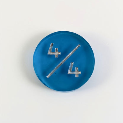 A top down photo of a blue 4/4 token with silver numbers sits on a white background.