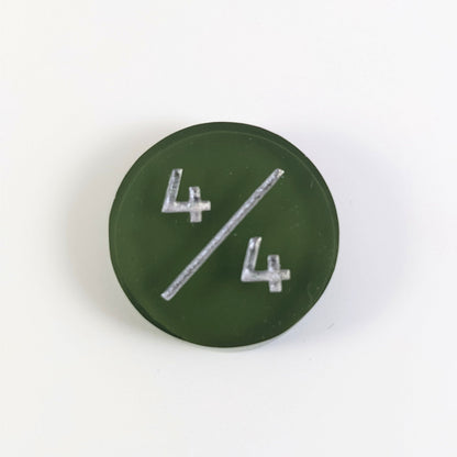 A top down photo of a dark green 4/4 token with silver numbers sits on a white background.