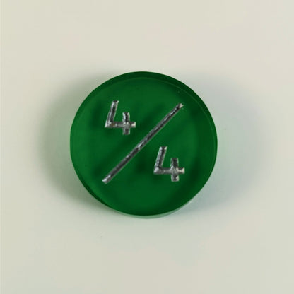 A top down photo of a green 4/4 token with silver numbers sits on a white background.