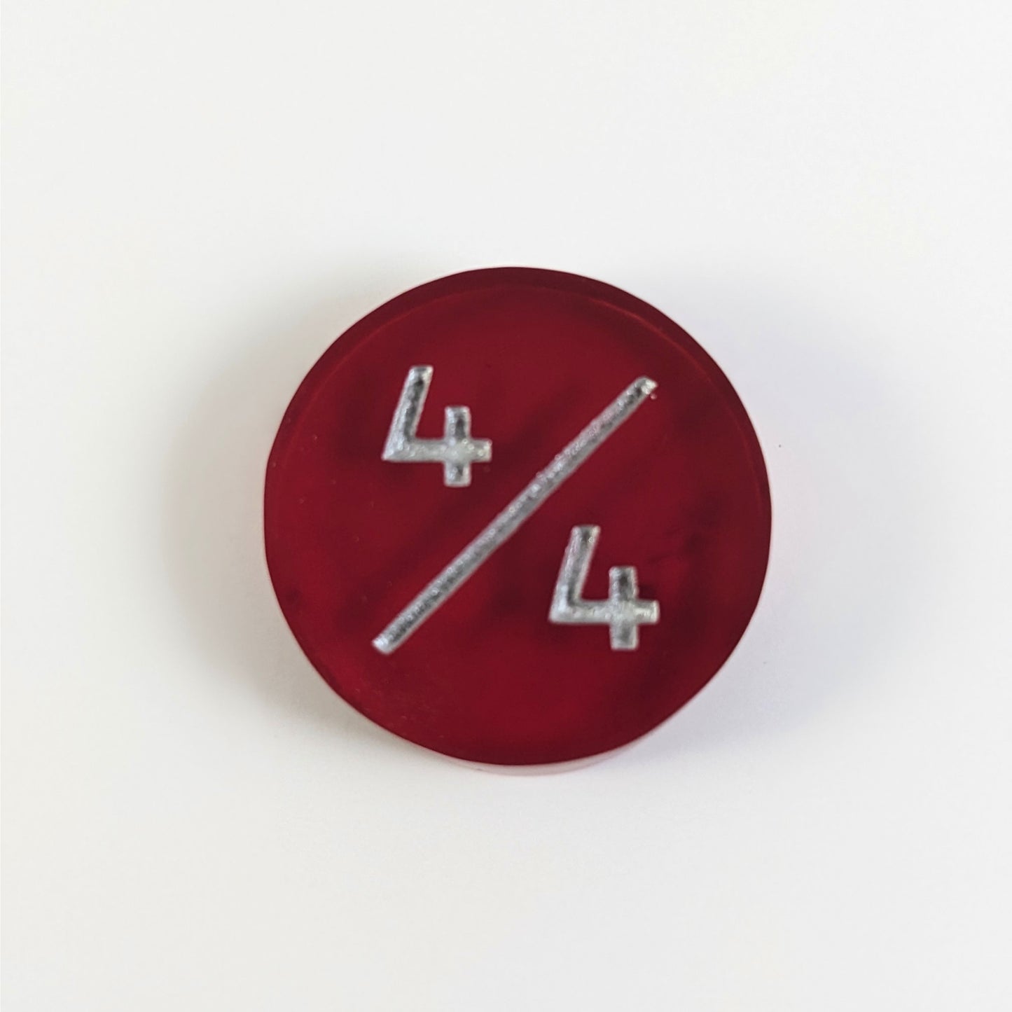A top down photo of a red 4/4 token with silver numbers sits on a white background.