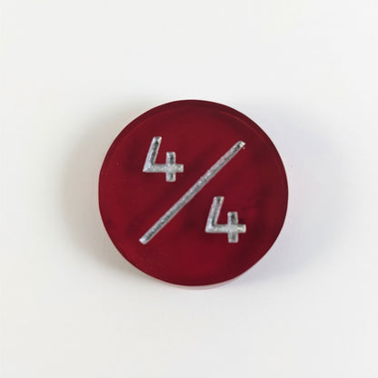 A top down photo of a red 4/4 token with silver numbers sits on a white background.