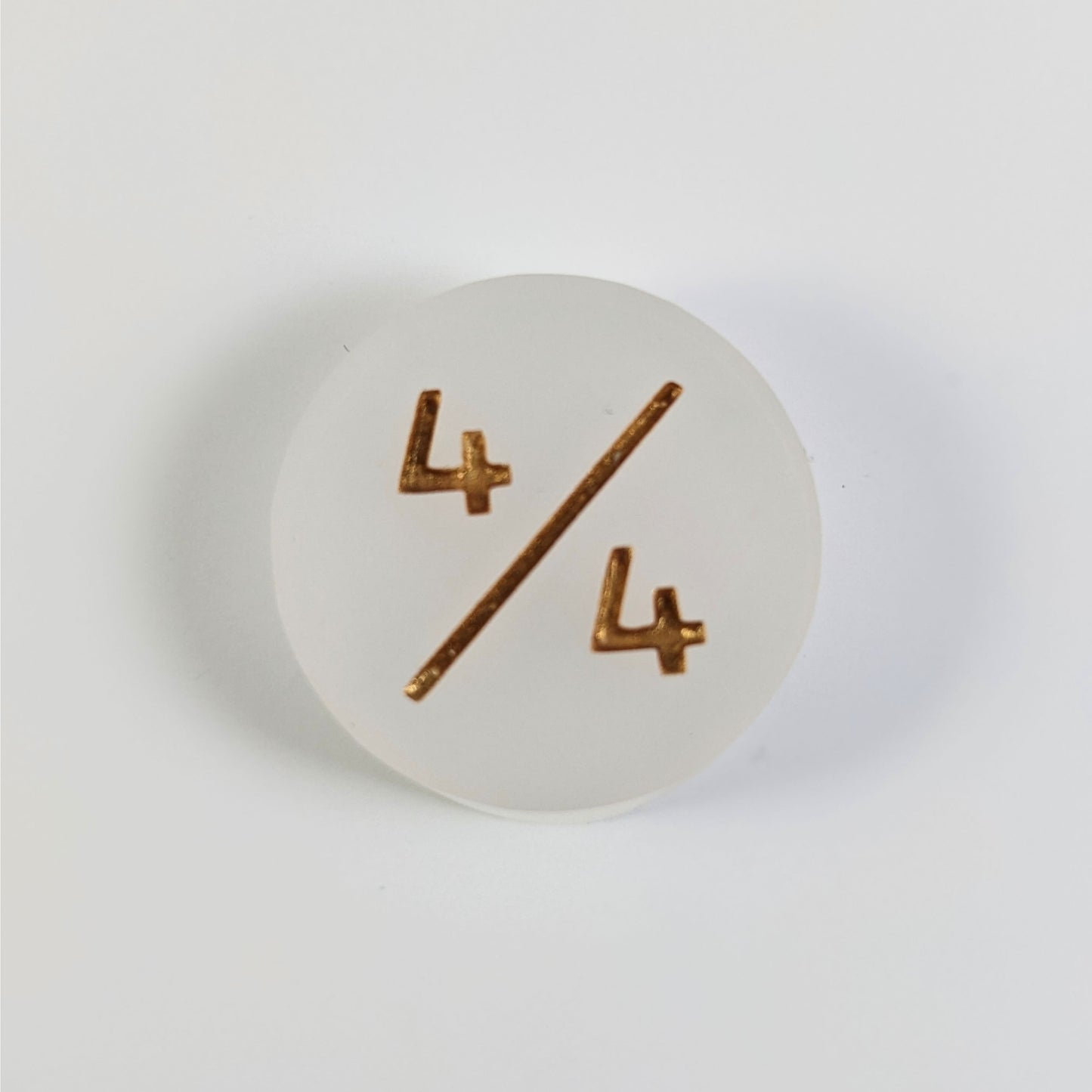 A top down photo of a white 4/4 token with gold numbers sits on a white background.