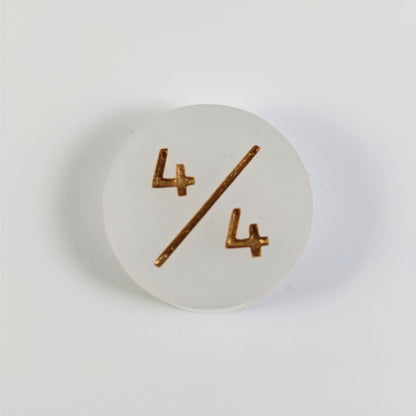 A top down photo of a white 4/4 token with gold numbers sits on a white background.
