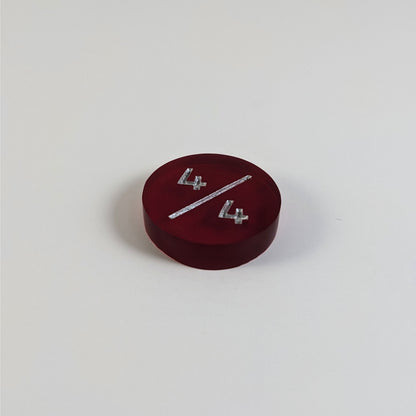 A low angle photo of a red 4/4 token with silver numbers sits on a white background.
