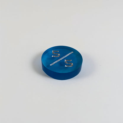 A low angle photo of a blue 5/5 token with silver numbers sits on a white background.