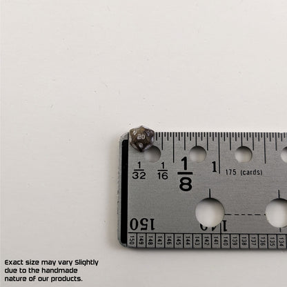 A size graphic of the d20 stud. The stud is brown with white numbers and centers the 20 face next to a ruler on a white background. The ruler shows the width of the stud as 7 mm or 0.27 in. The lower lefthand corner has a disclaimer that reads, "Exact size may vary slightly due to the handmade nature of our products."