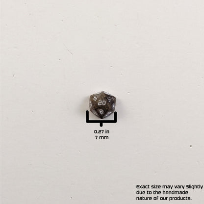 A size graphic of the d20 stud. The stud is brown with white numbers and centers the 20 face on a white background. The graphic overlay shows the width of the stud as 7 mm or 0.27 in. The lower righthand corner has a disclaimer that reads, "Exact size may vary slightly due to the handmade nature of our products."