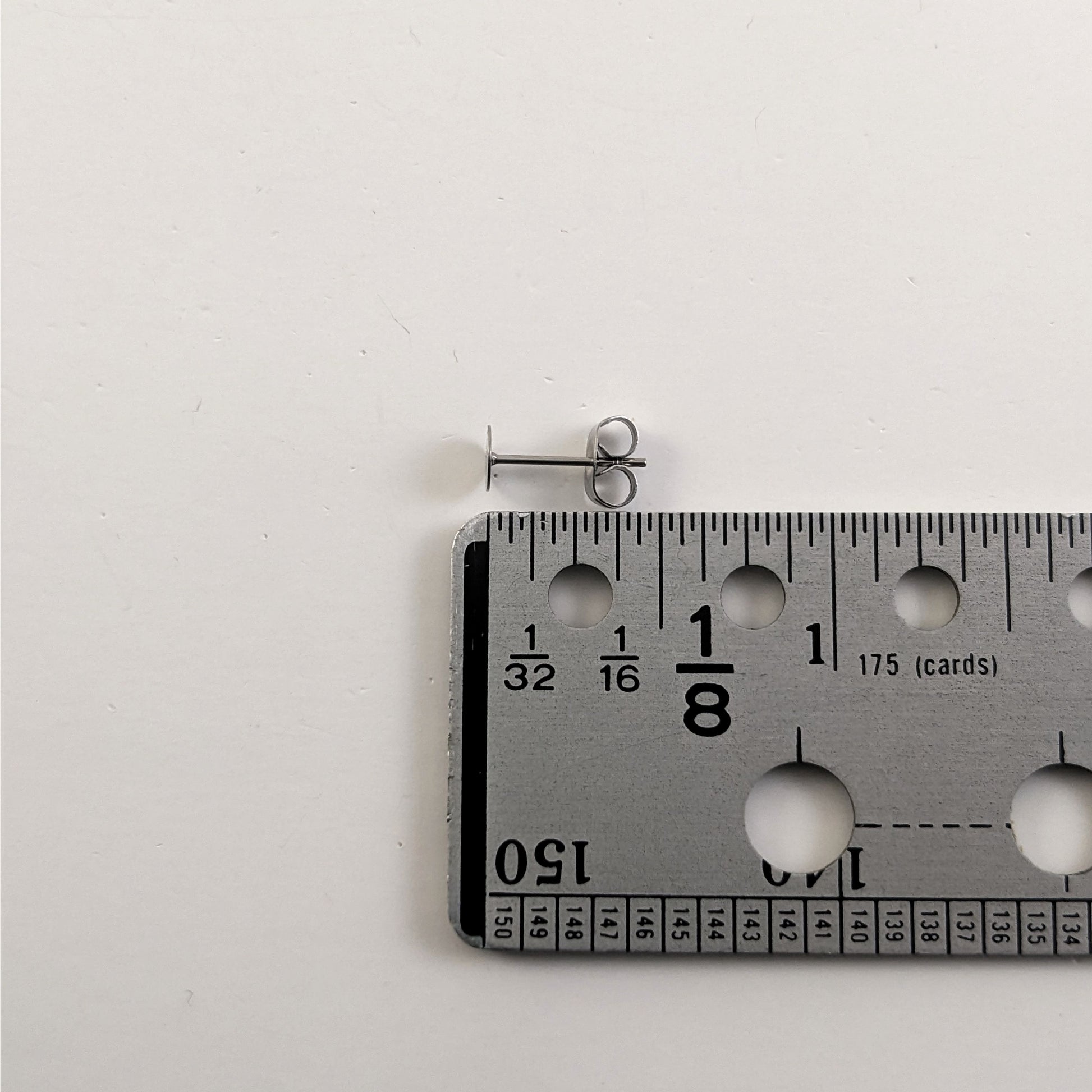 A size graphic of an earring post and butterfly back next to a ruler and on a white background. It shows the length of the post as 12 mm or 0.47 in.