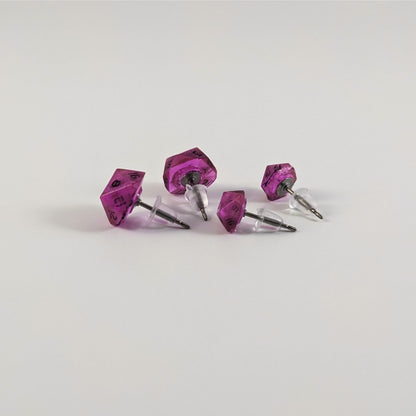 Two pairs of handmade d20 earrings that are amethyst purple with black numbers turned to show the titanium hardware and bell shaped rubber backs.