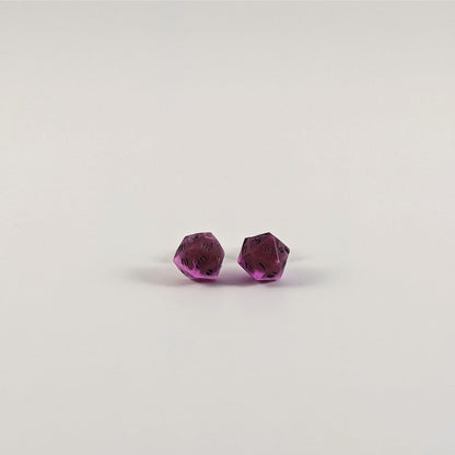 A single pair of the smaller size handmade d20 earrings with titanium hardware that are amethyst purple with black numbers on a white background. The earring on the left centers the 20 face and the earring on the right centers the 1 face.