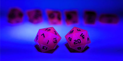 A straight on photo of a standard set of DnD dice that are deep purple with black numbers focusing on 2 d20s in the center. The d20 on the left has the 1 face centered and the d20 on the right has the 20 face centered. The other 6 dice are lined up in the background but are out of focus, while the d20s are in sharp focus. The image is light with a UV light, tinting the image blue and causing the dice to react with a pick glow.