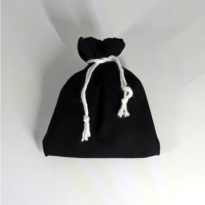 A small, handmade dice bag that is black is tied closed on a white background.