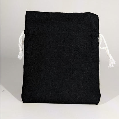 A small, handmade dice bag that is black stands upright on a white background.
