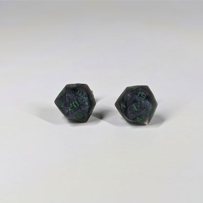 A single pair of the larger size handmade d20 earrings that are black and silver with acid green numbers on a white background. The earring on the left centers the 20 face and the earring on the right centers the 1 face.
