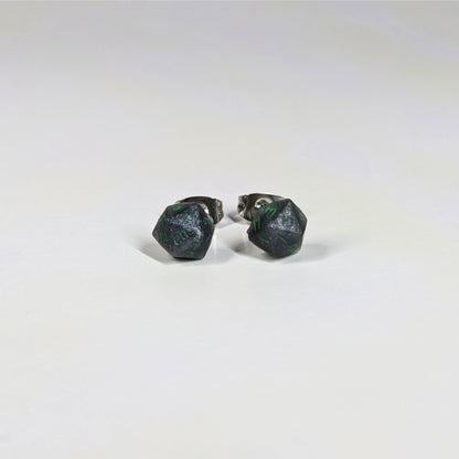 A single pair of the smaller size handmade d20 earrings that are black and silver with acid green numbers on a white background. The earring on the left centers the 20 face and the earring on the right centers the 1 face.